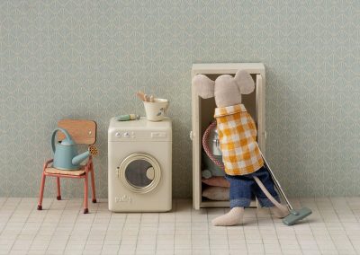 Dad mouse putting vacuum cleaner in cupboard beside washing machine